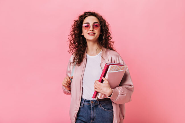 Cute lady in pink outfit and sunglasses holding book